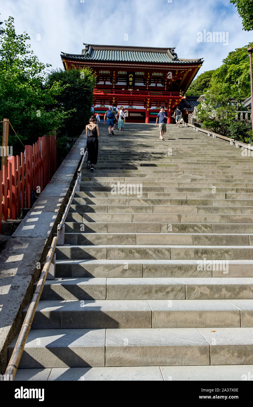Tourists climbing stone steps to a red wooden temple near Tokyo in Japan Stock Photo