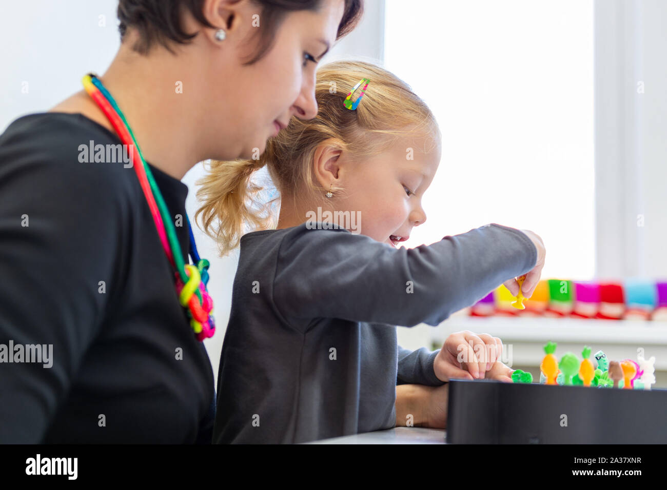 Toddler girl in child occupational therapy session doing sensory playful exercises with her therapist. Stock Photo