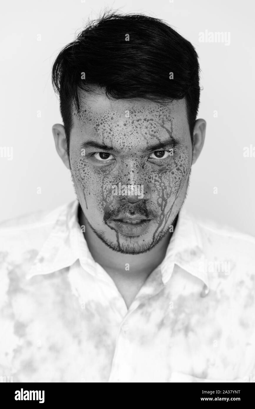Face of young crazy Asian man looking at camera with blood on face Stock Photo