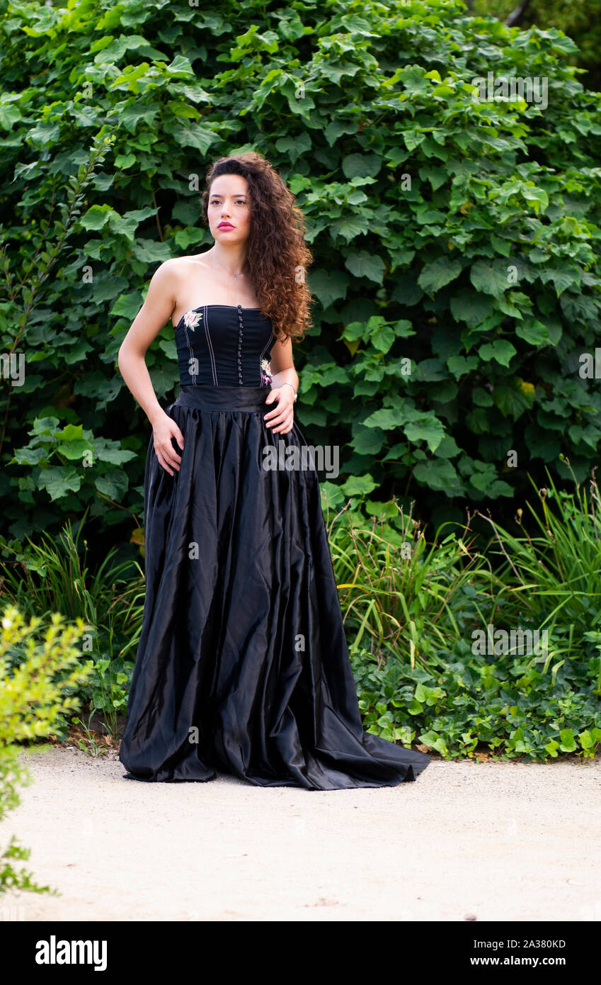 Beautiful young woman wearing elegant black frock in a park Stock Photo Alamy