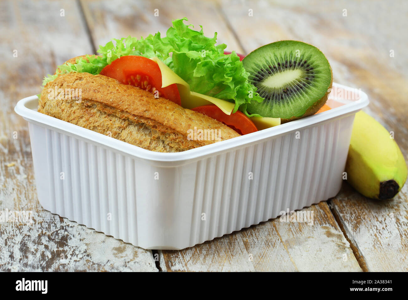 Healthy packed lunch box containing whole grain cheese sandwich, kiwi