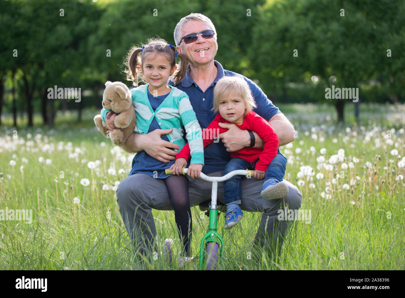 Happy Older grandfather with two kids lying on grass In park Stock Photo