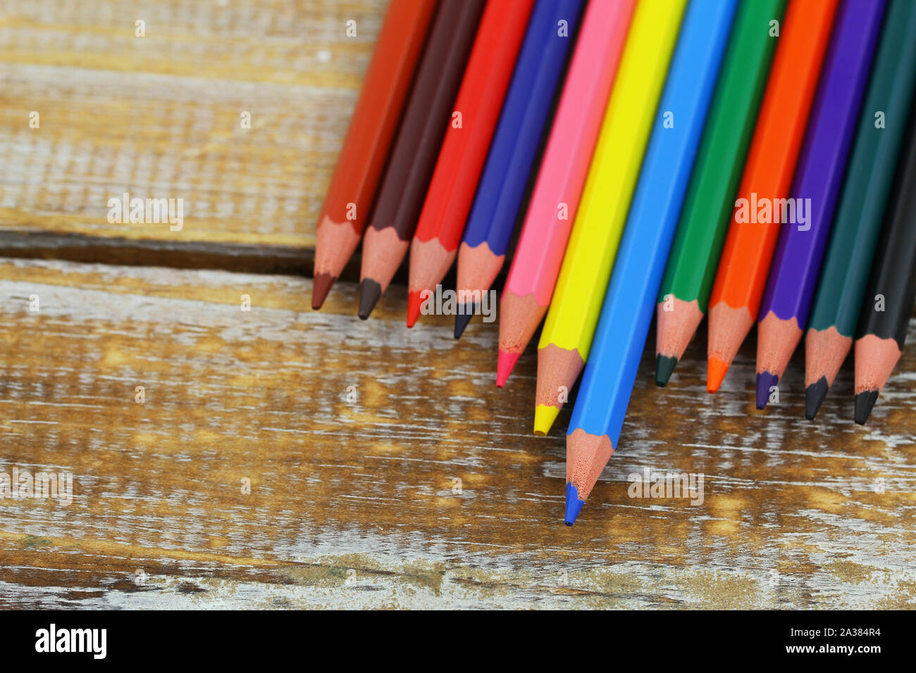 Colorful pencils spread out on wooden surface with copy space Stock Photo