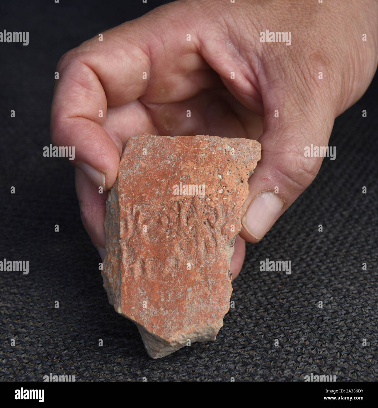 En Esur, Israel. 06th Oct, 2019. A man holds a seal impression of a man hands lifted, discovered during excavations of a vast 5,000 cosmopolitan and planned city from the Early Bronze Age, one of the first and largest of the ancient Near East, excavated by the Israeli Antiquities Authority in En Esur, Israel, on Sunday, October 6, 2019. The En Esur archaeological site, located near Wadi Ara, was discovered prior to the construction of a highway interchange and revealed a massive city where 6,000 people lived. Photo by Debbie Hill/UPI Credit: UPI/Alamy Live News Stock Photo