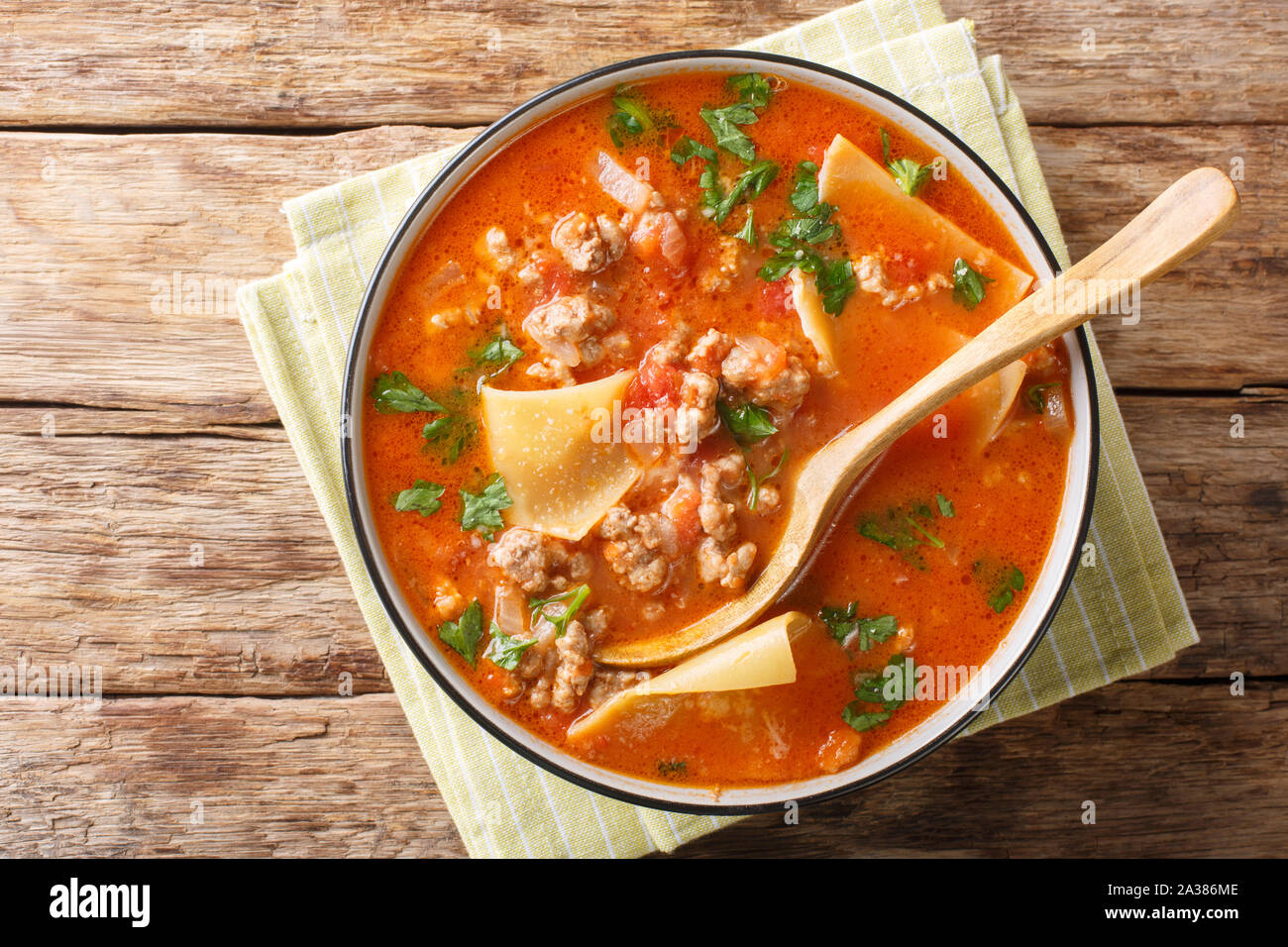 Portion of rich lasagna soup close-up in a plate on the table. Horizontal top view from above Stock Photo