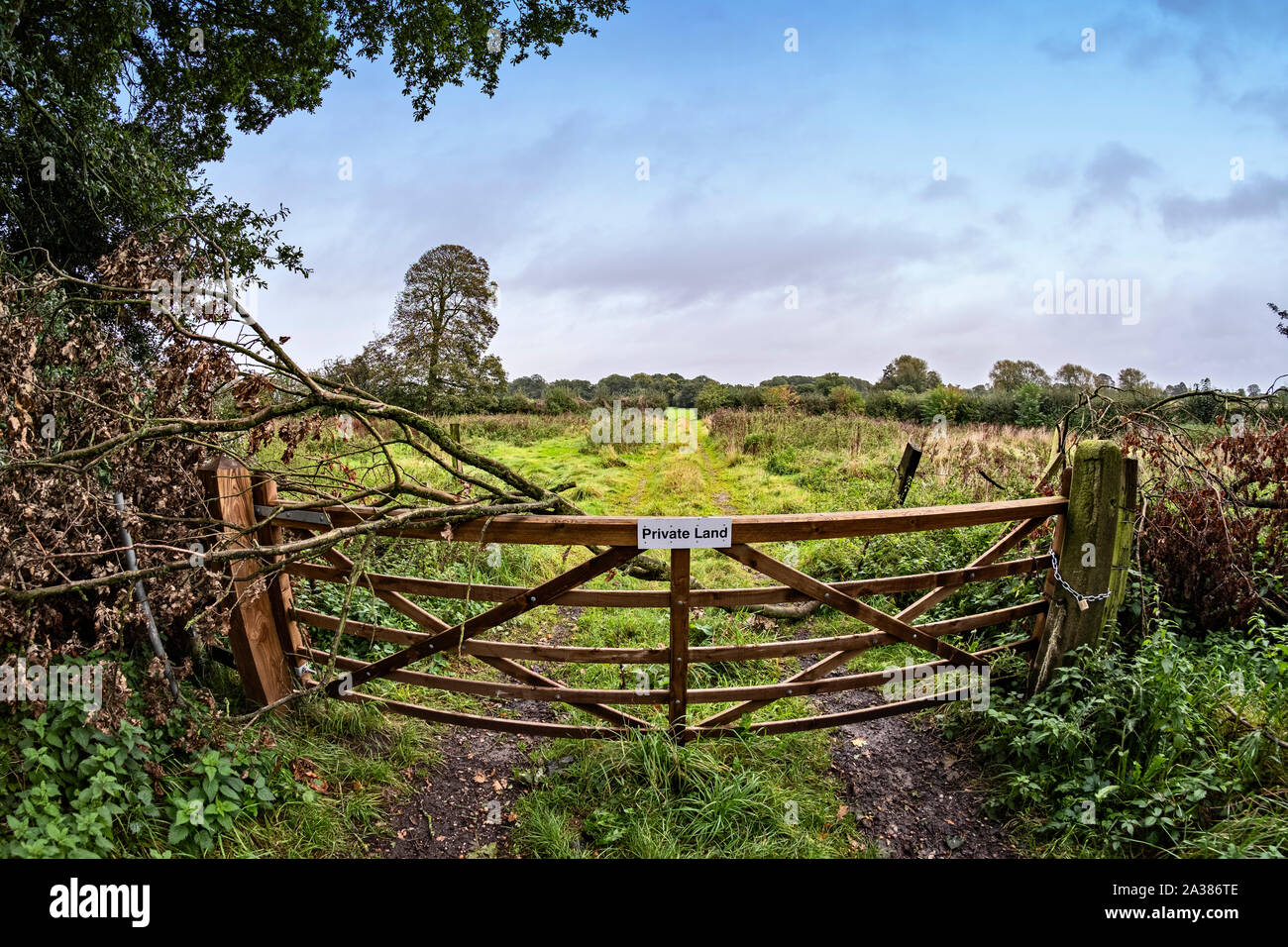 View over gate into private land with warning sign in Cheshire UK Stock Photo