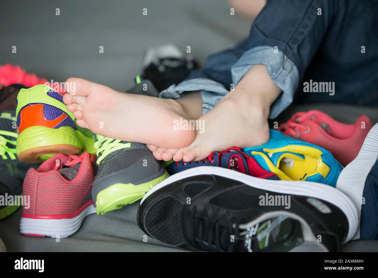 Bare feet in a pile of shoes. Children s foot on the background of