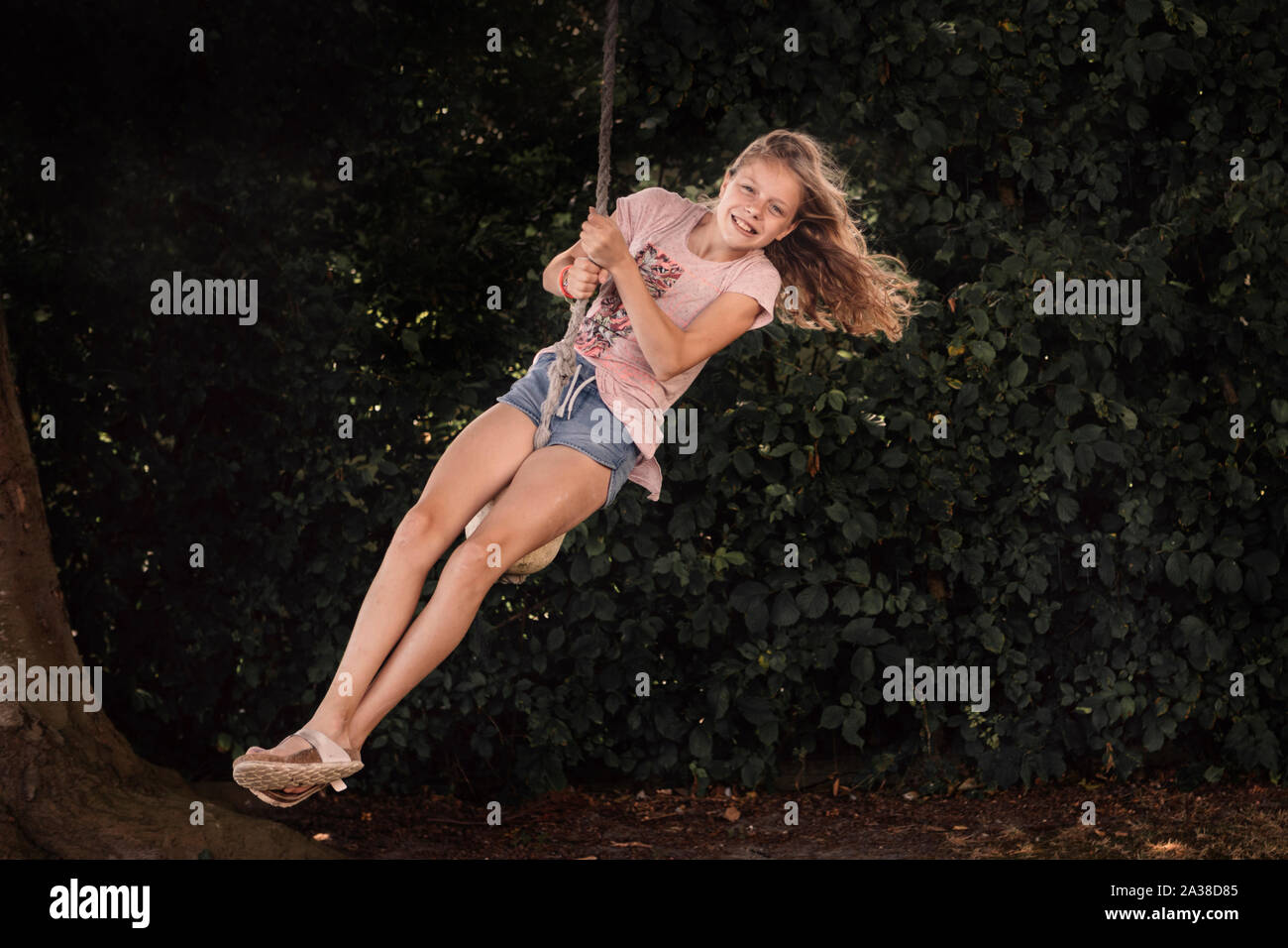 Smiling Girl on a rope swing in the garden, Denmark Stock Photo