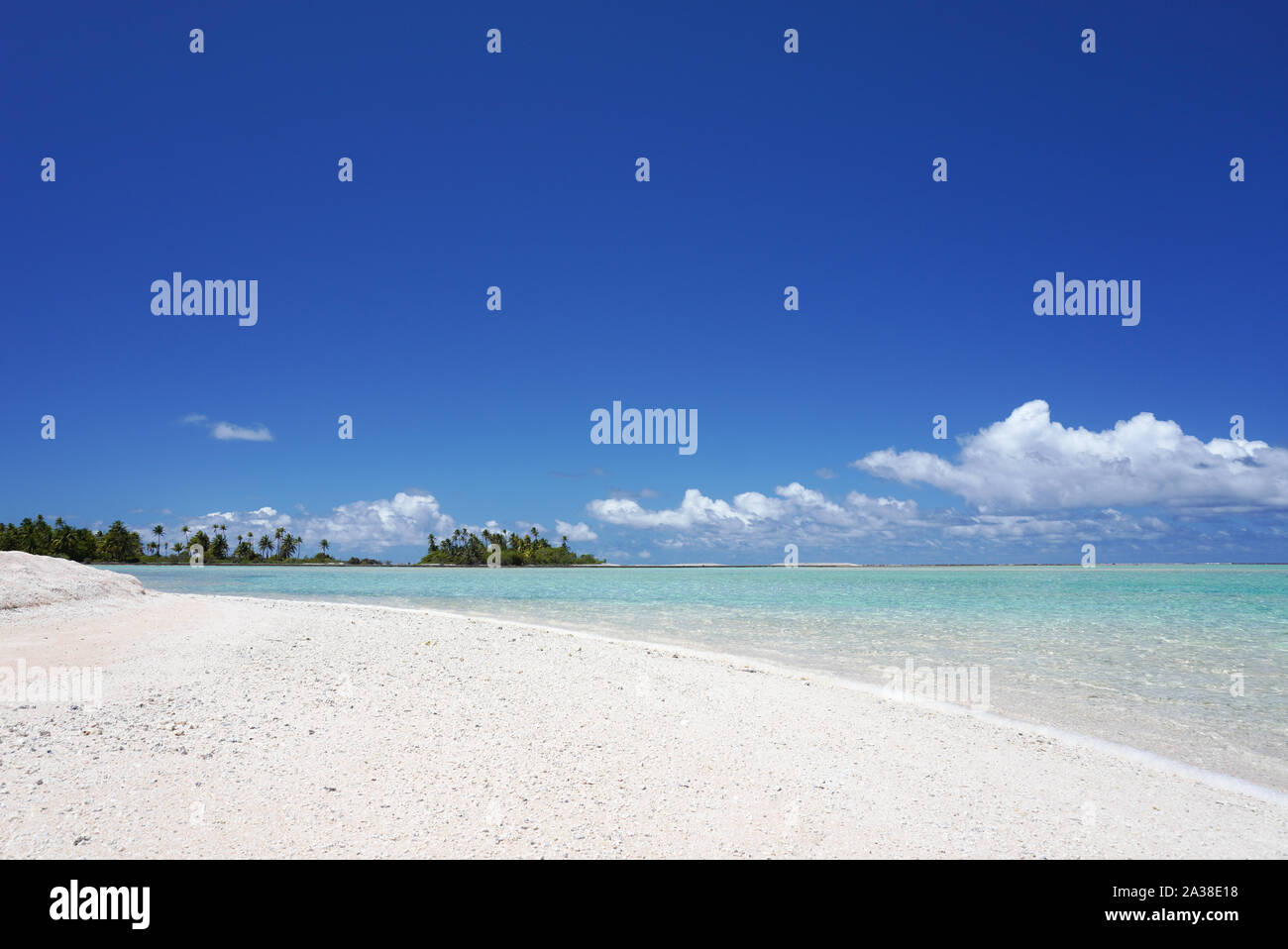 Turquoise water washes up on a white sandy beach with palm trees on a tropical island Stock Photo