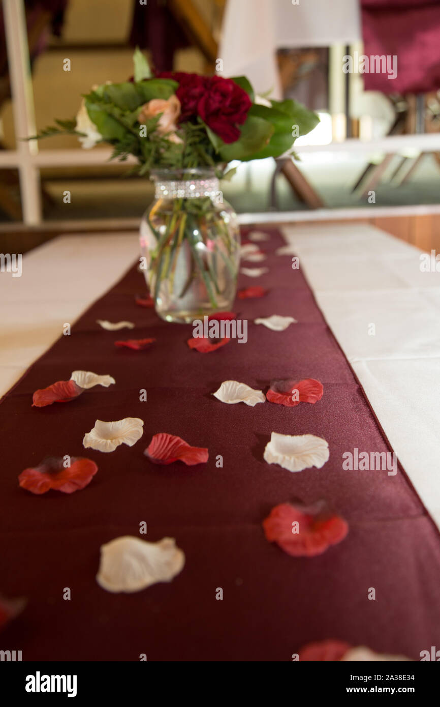 Flower petals and bouquet of flowers on a dining table Stock Photo