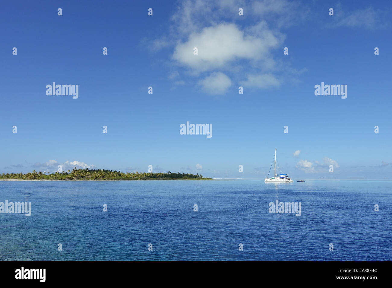 A catamaran anchors in a lagoon under a blue sky off the island of Fakarava in French Polynesia Stock Photo