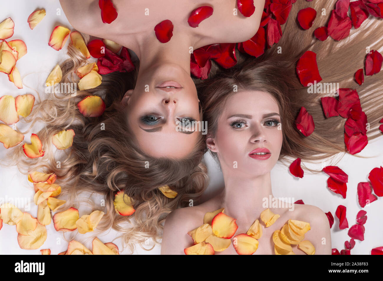 Close Up Two Girlfriends Lying In A Spa Salon Among Rose Petals