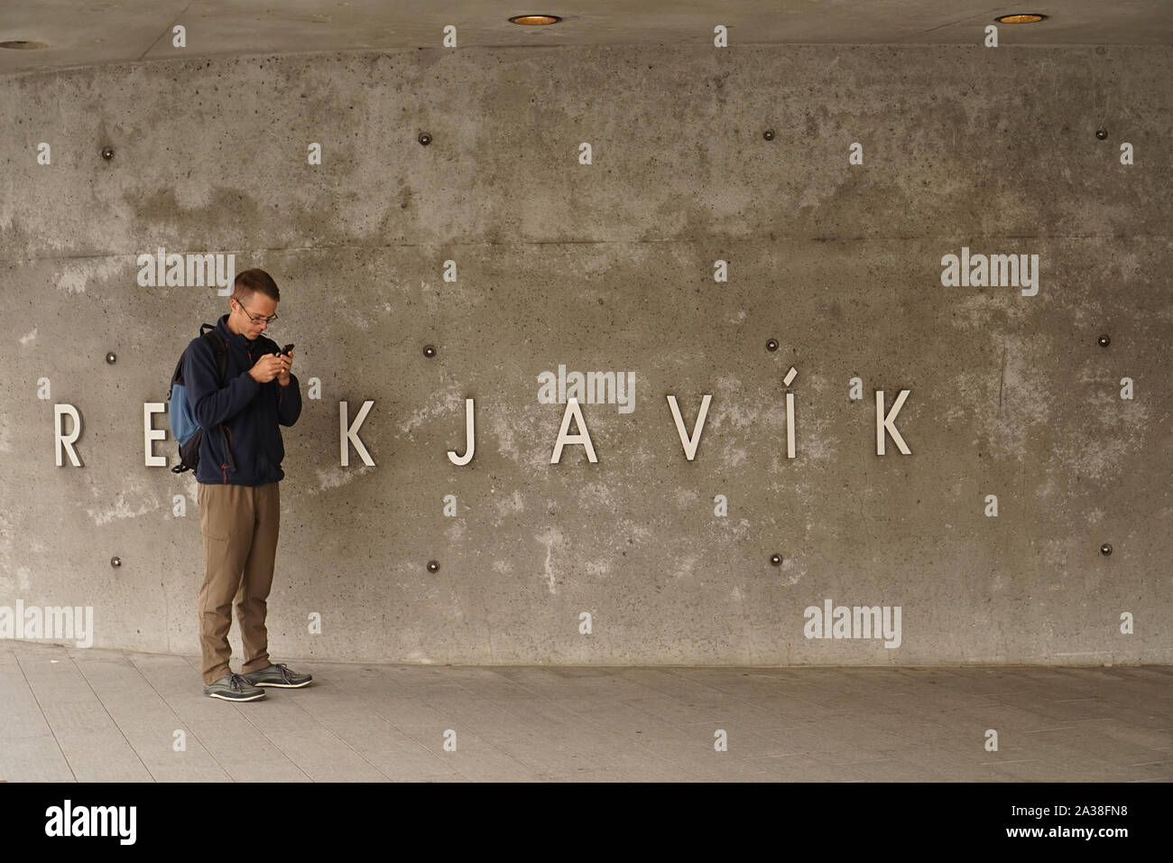 Man looking at phone standing by 'Reykjavik' sign Stock Photo