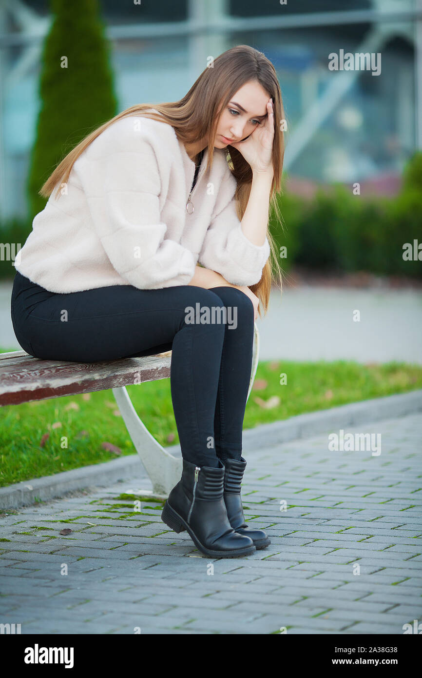 Upset woman with problems sitting on a bench Stock Photo - Alamy