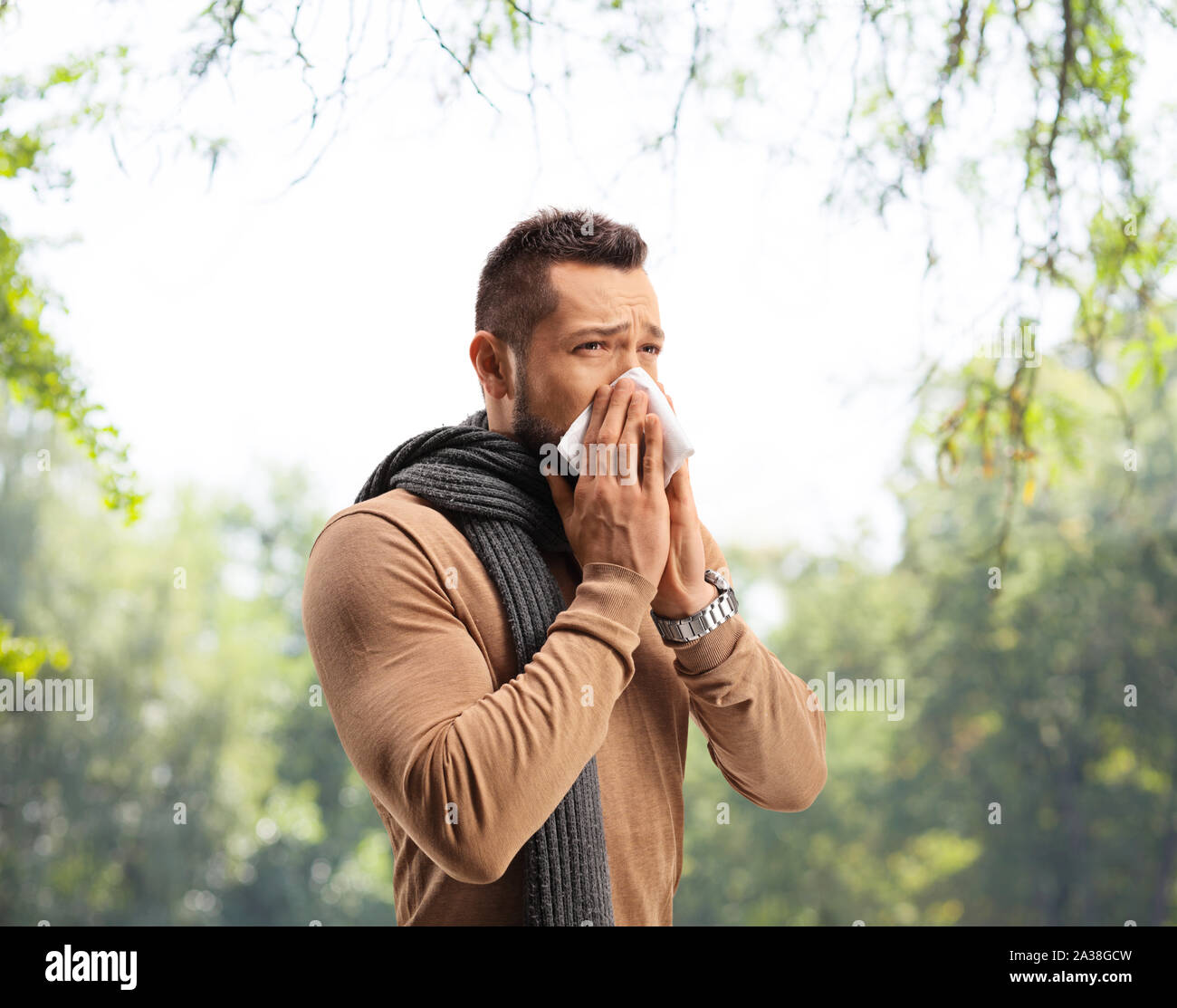 Young man blowing nose in a park Stock Photo