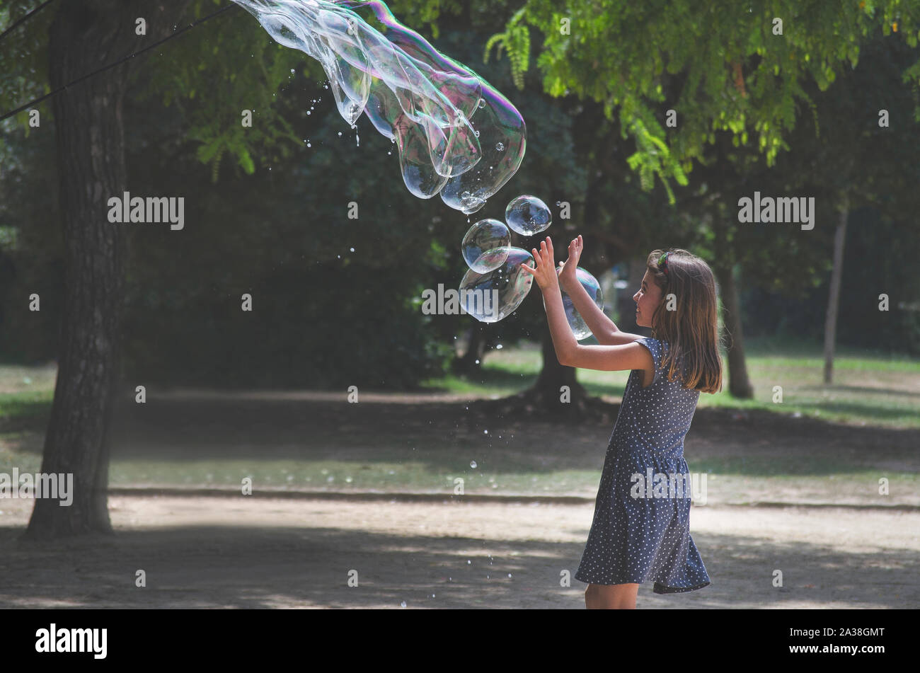 Girl playing with giant bubbles in a park, France Stock Photo