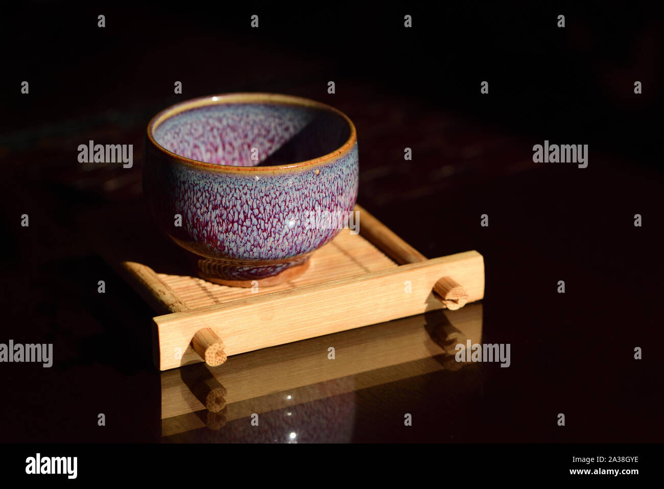Close-up of a ceramic empty ceramic teacup on a small bamboo board against a dark background at a Chinese tea ceremony Stock Photo