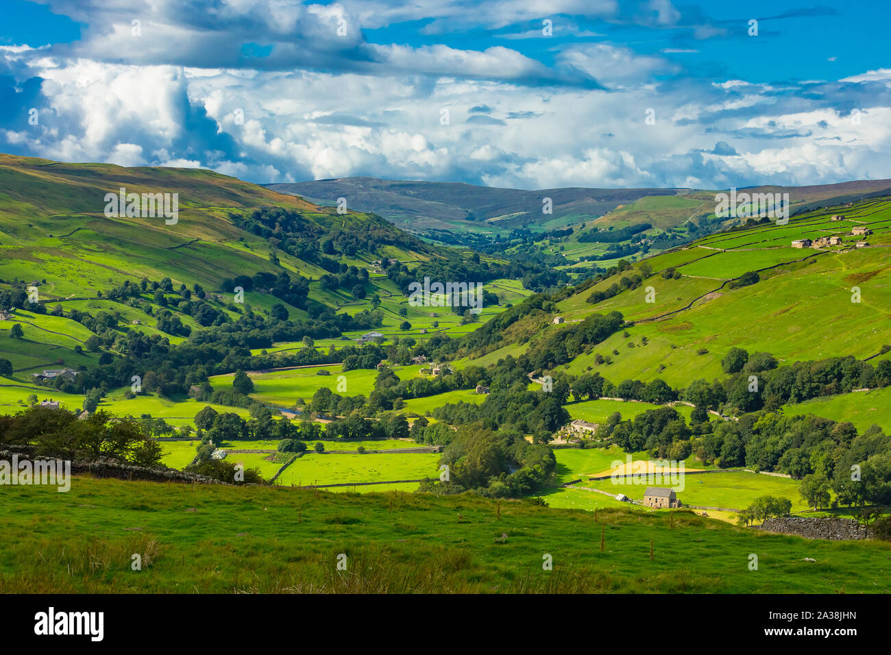 The Yorkshire Dales. Askrigg road to Gunnerside in Swaledale. Farmsteads, drystone walling, fields and meadows with the River Swale running through Stock Photo