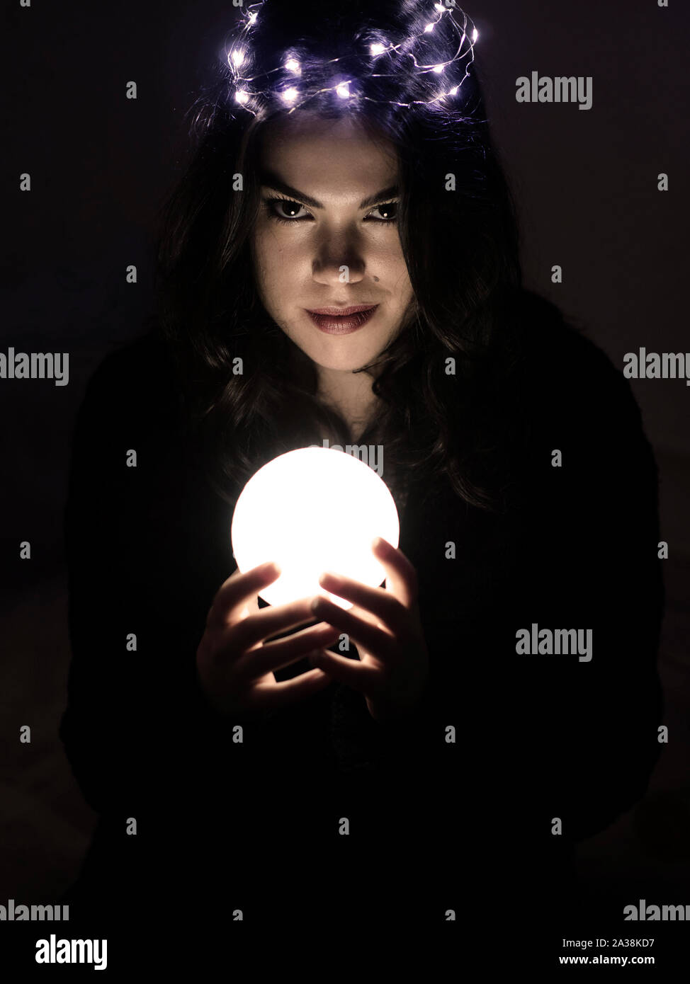 beautiful young woman with fairy lights on her head holding a glowing