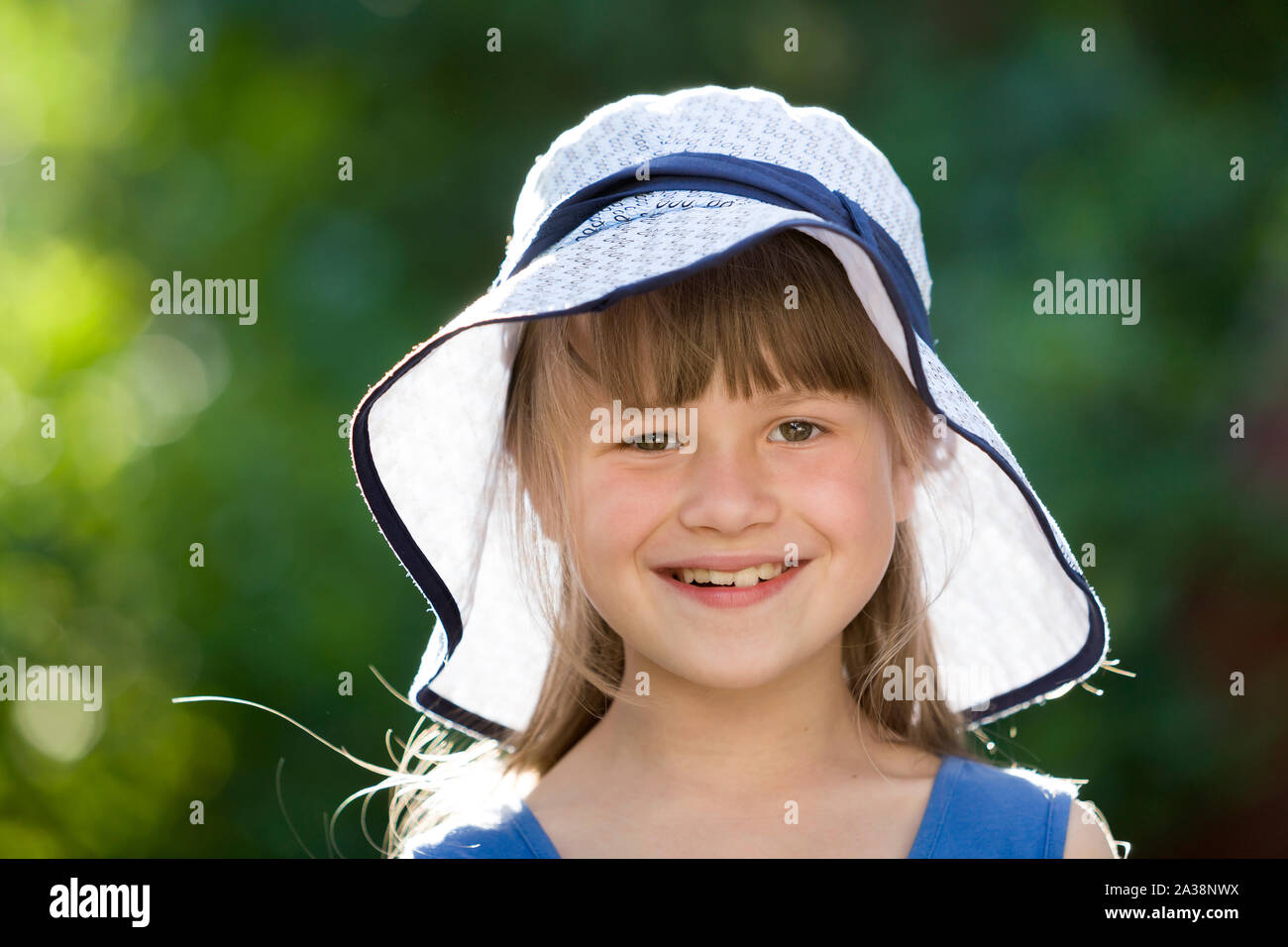 Close-up portrait of happy smiling little girl in a big hat. Child ...
