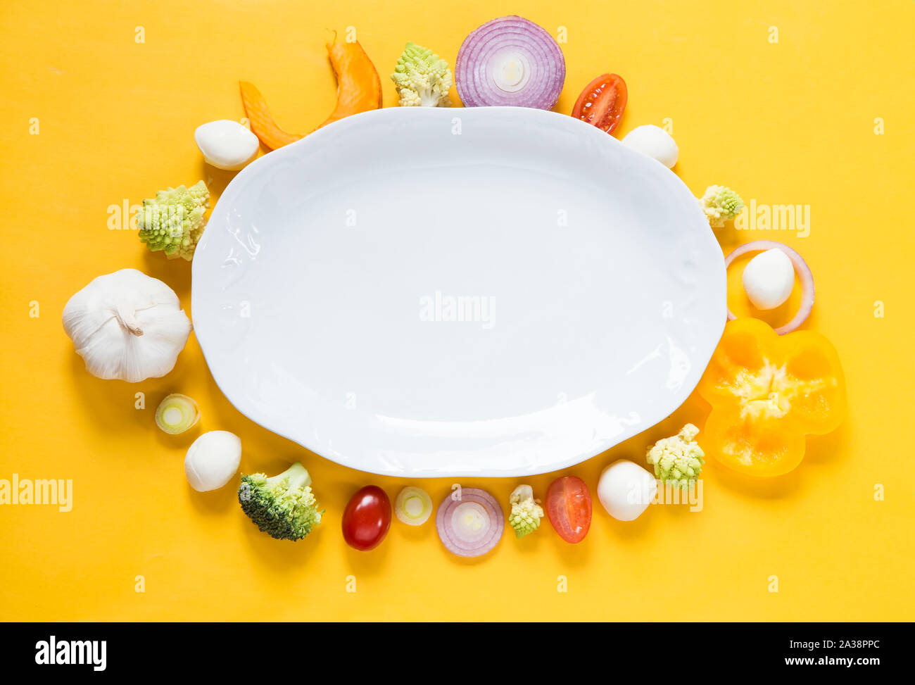 Vegetables with a white plate on yellow background Stock Photo