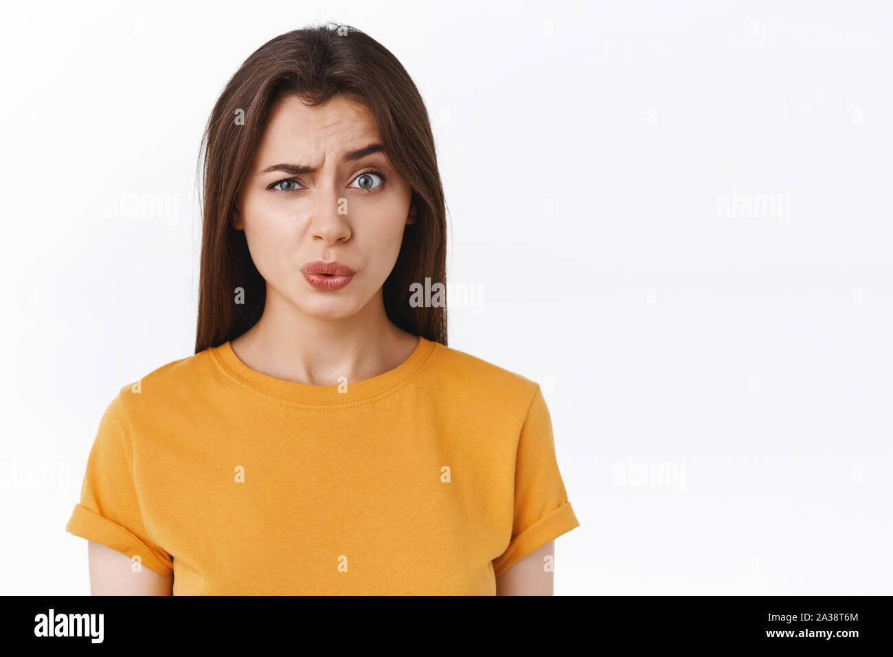 Ouch it probably hurts. Pity good-looking modern brunette woman in yellow t-shirt cringe and grimace as seeing someone got punched in face, folding Stock Photo