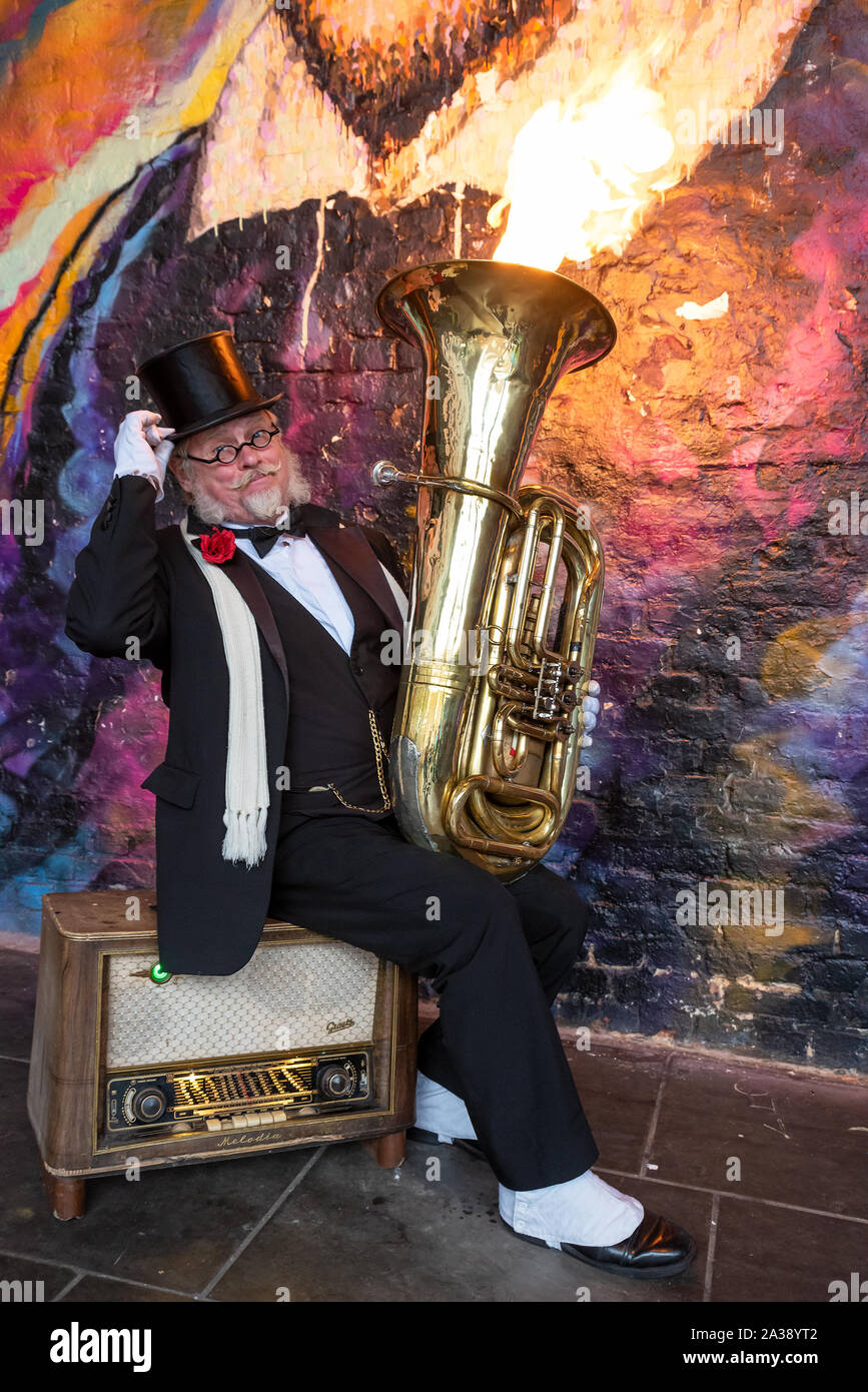 Krysztof Werkowicz is an international busking sensation from Poland who plays a custom-made tuba that belches flames out of the top. Pictured here busking in the Clink Street Tunnel, Bankside, London, UK. Behind Krysztof  is the William Shakespeare mural painted by Australian street artist Jimmy C. Stock Photo