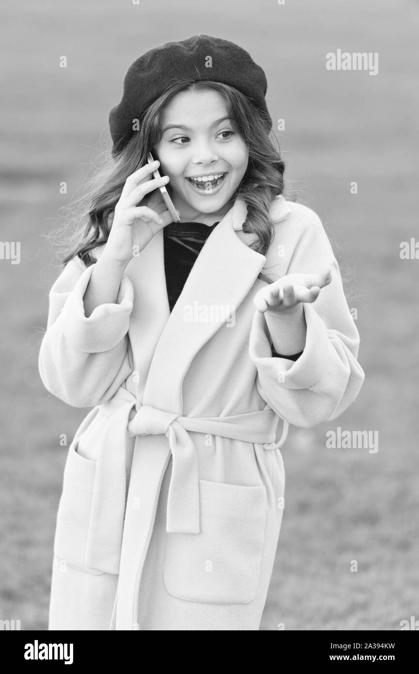 Totally happy. fall season. happy childhood. small child with phone. beauty in autumn coat. cheerful little girl in yellow coat. parisian girl kid in french beret speak on phone. autumn fashion. Stock Photo