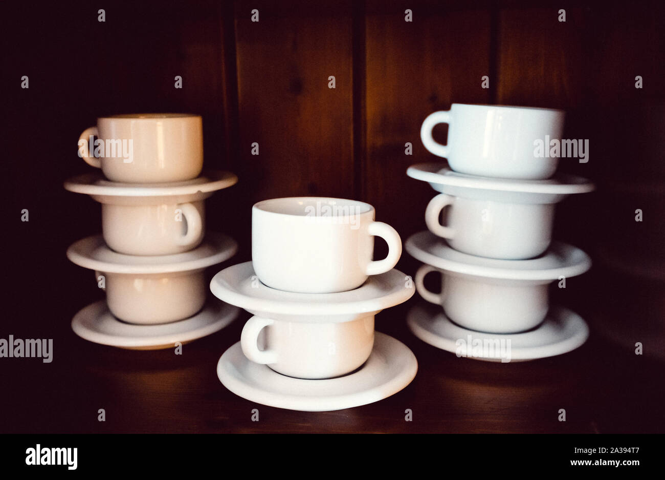 Set of white cups in a cupboard, piled Stock Photo