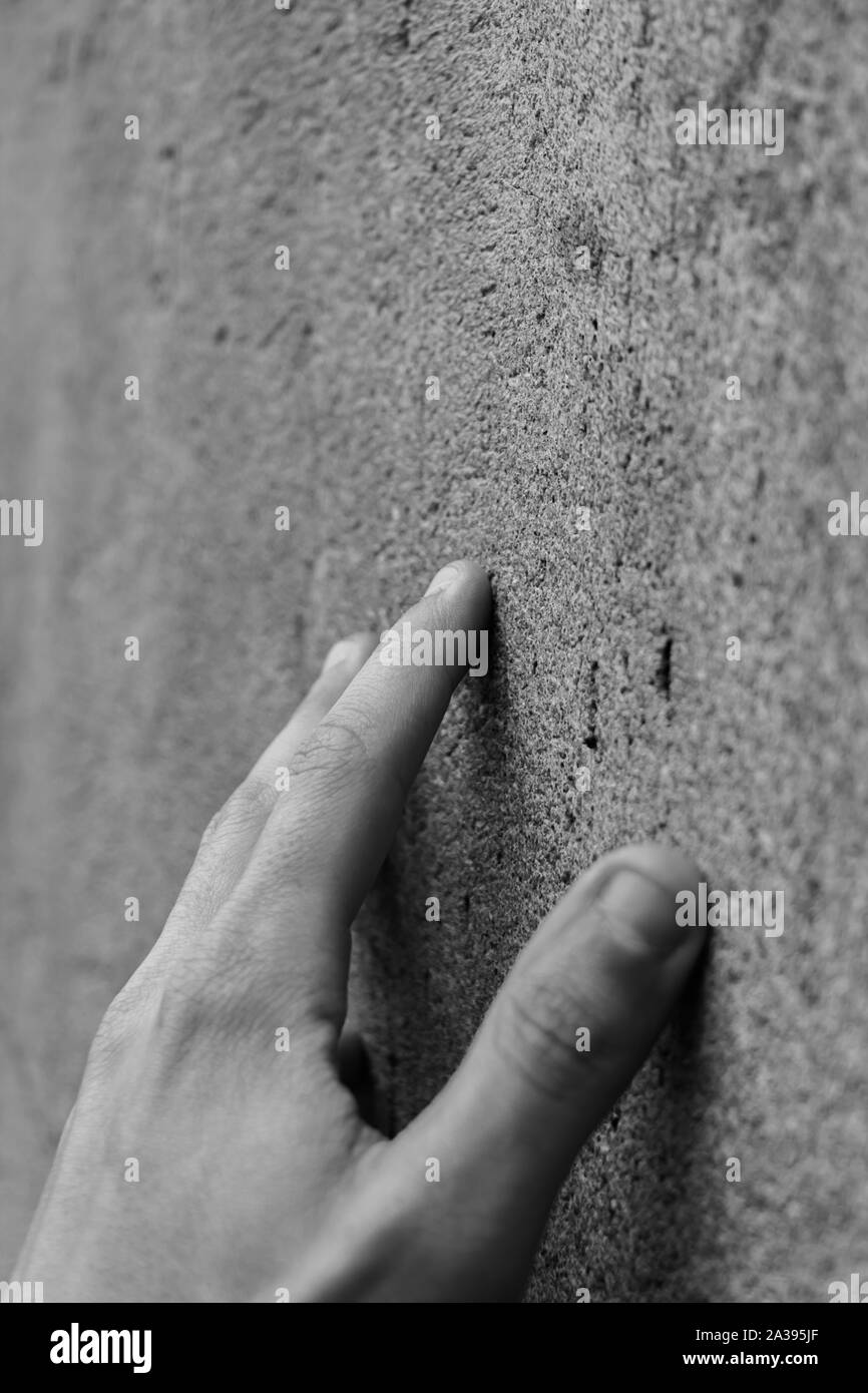 A black and white picture of a hand touching the actual wall at the Berlin Wall Memorial. Stock Photo