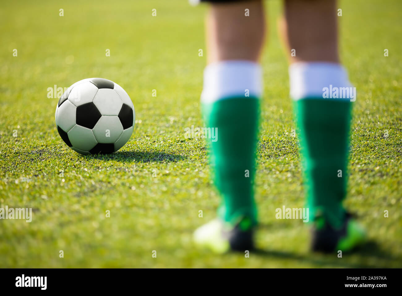 One soccer football player standing next to ball ready to kick. Legs of