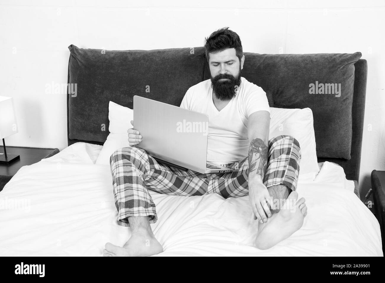 Man surfing internet or working online. Hipster bearded guy pajamas freelance worker. Remote work concept. Online life. Social networks internet addiction. Online shopping. Whole world in his laptop. Stock Photo