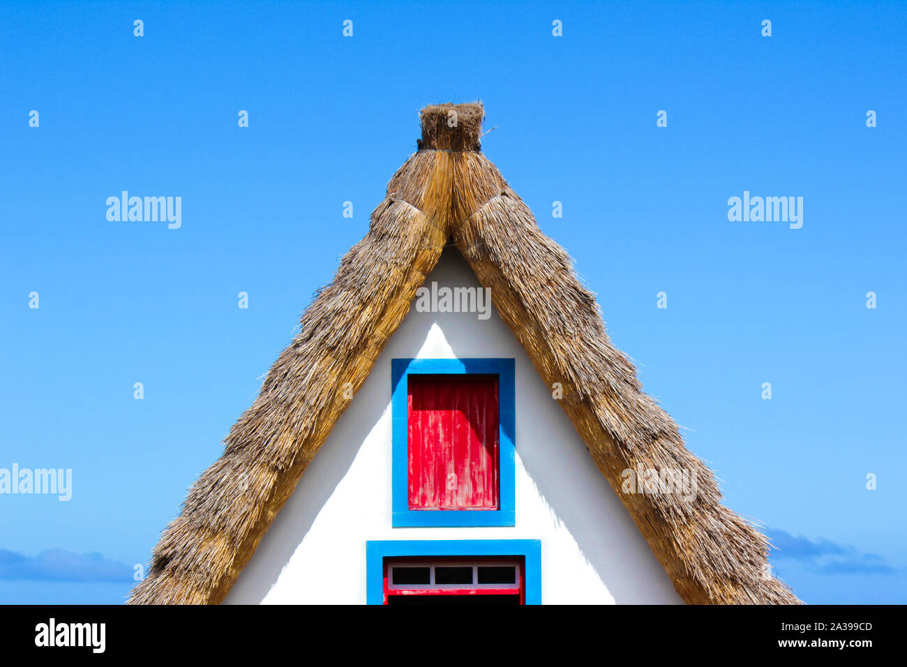 Detail of the front side facade of the traditional house in Santana, Madeira Island, Portugal. Typical thatched roof, colorful facade in white, red and blue colors. Portuguese architecture. Stock Photo
