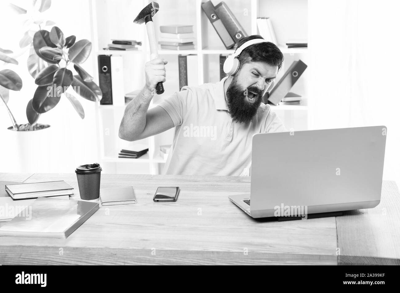 Man bearded guy headphones office swing hammer on computer. Slow internet connection. Outdated software. Computer lag. Reasons for computer lagging. How fix slow lagging system. Hate office routine. Stock Photo
