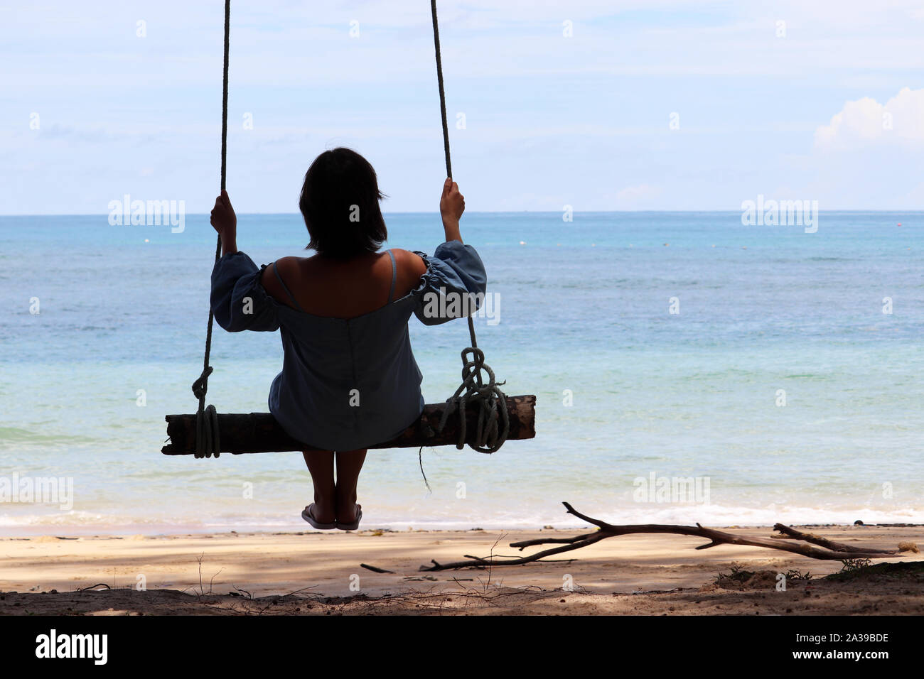 Silhouette of a girl swinging on a swing against the blue sea. Beach holidays, concept of freedom, happiness and romance Stock Photo
