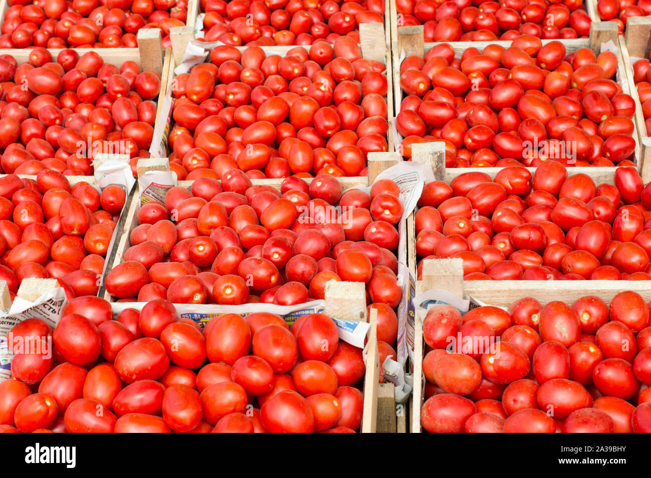 Red ripe tomatoes lie for sale in wooden boxes in the open air market. Stock Photo