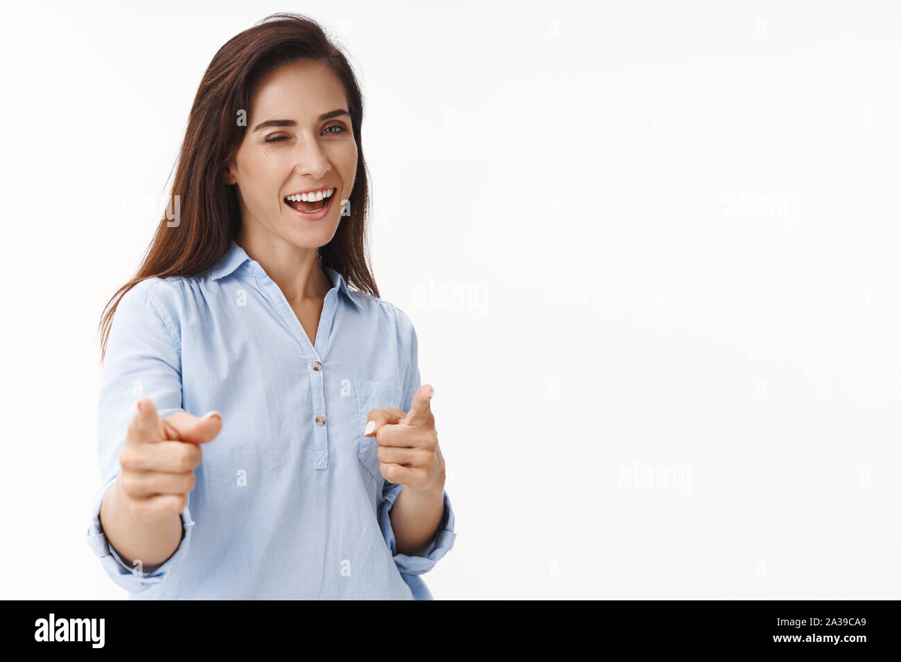 Successful ambitious brunette woman 30s congratulate coworker good job, pointing camera finger pistols, wink joyfully entertained, smiling delighted Stock Photo