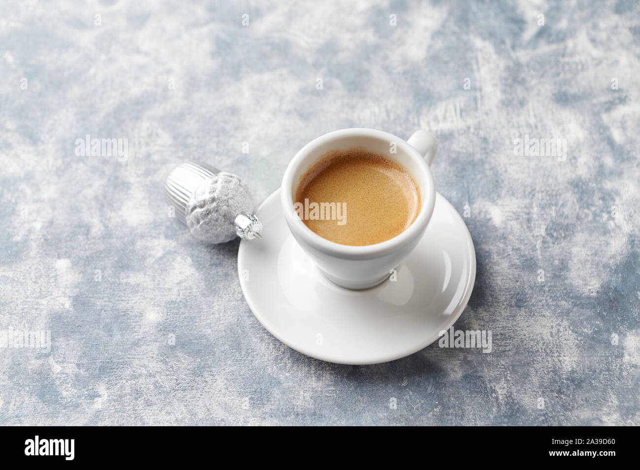 Cup of coffee and silver Christmas bauble on bright wooden background. Copy space. Stock Photo