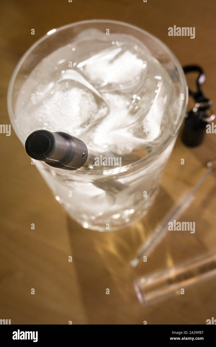 Reusable Stainless Plastic Free Steel Straw in use in a water glass, USA Stock Photo