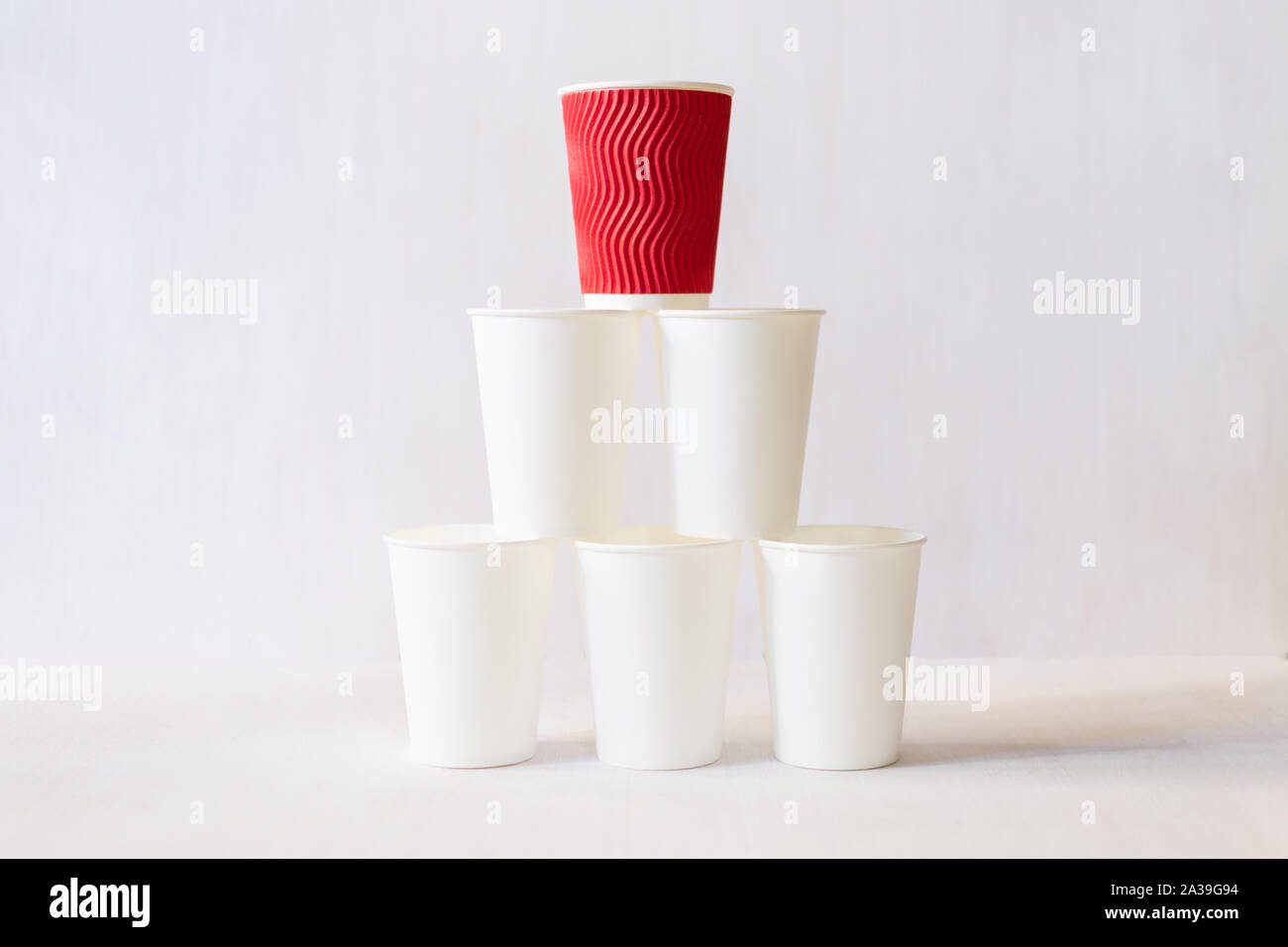 https://c8.alamy.com/comp/2A39G94/red-paper-coffee-cup-stands-on-top-of-white-paper-cups-pyramid-white-background-copy-space-2A39G94.jpg