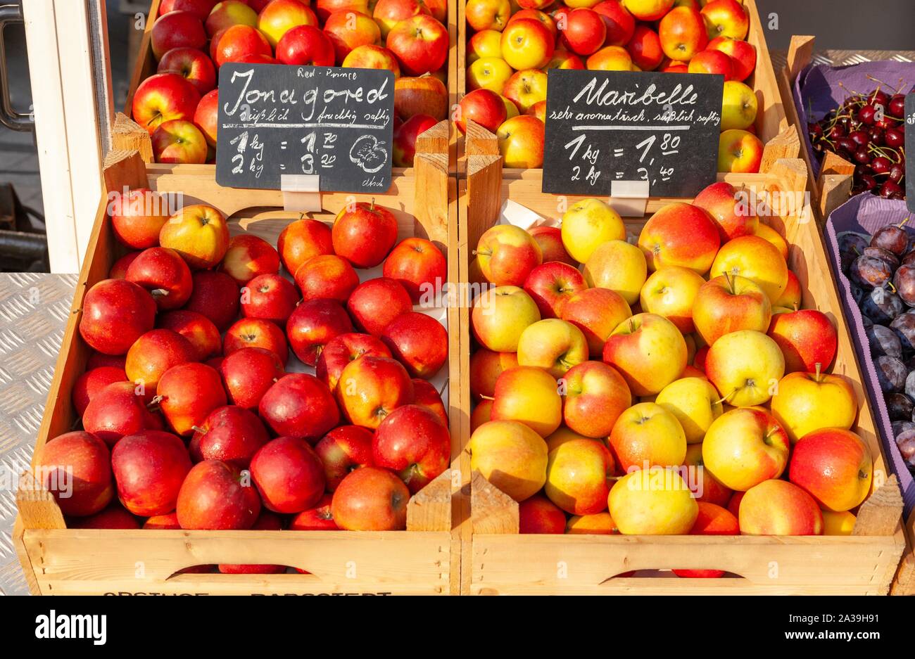 Fresh apples with price tags in wooden boxes at a market stall, Germany