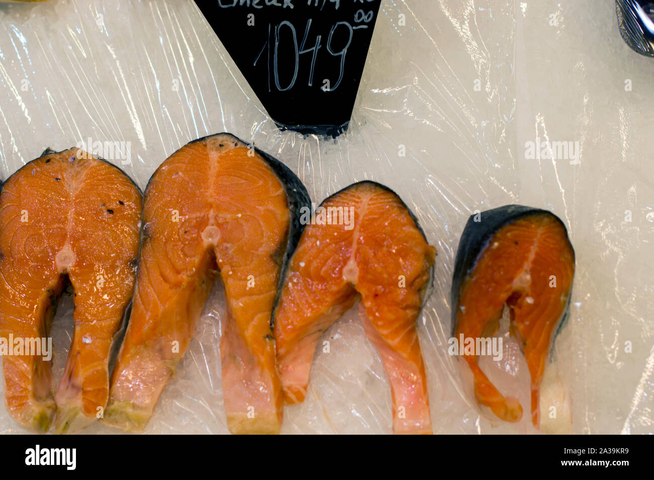 Appetizing slices and pieces of cod fish lie on the ice of the counter, ready for sale in a supermarket. Close-up. Stock Photo