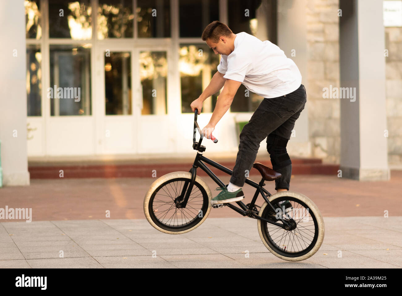 The guy rides on the BMX, standing on the rear wheel. Stock Photo