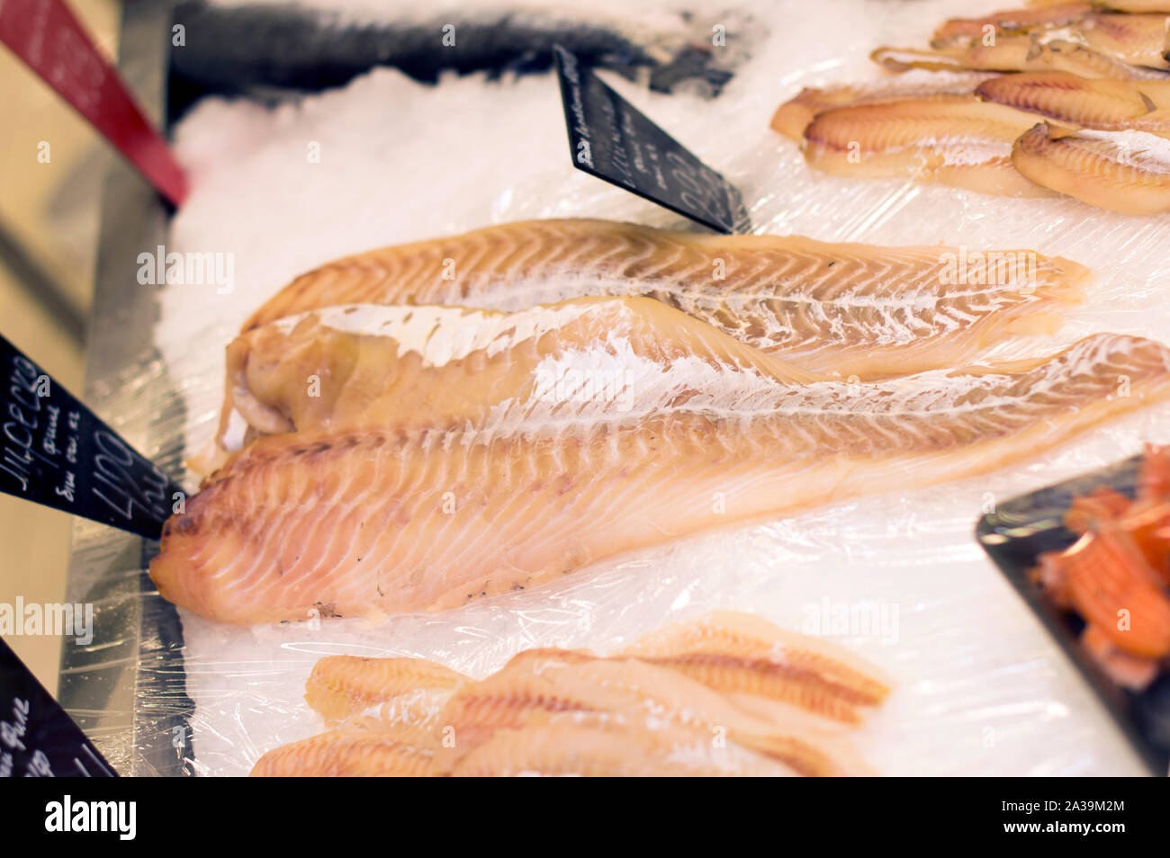 Appetizing slices and pieces of cod fish lie on the ice of the counter, ready for sale in a supermarket. Close-up. Stock Photo