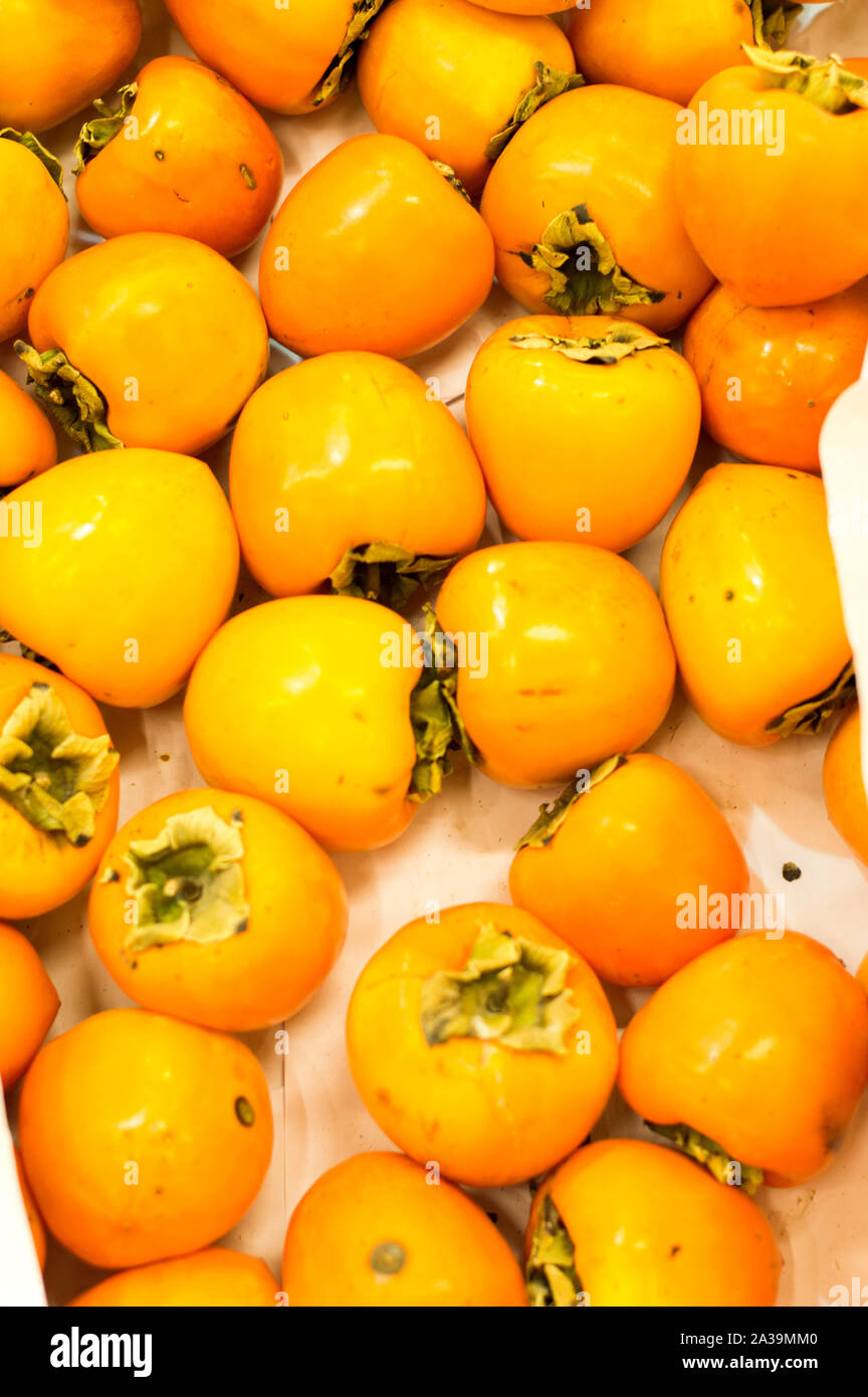 Persimmon fruits in a wooden box prepared for sale at the grocery market. Stock Photo