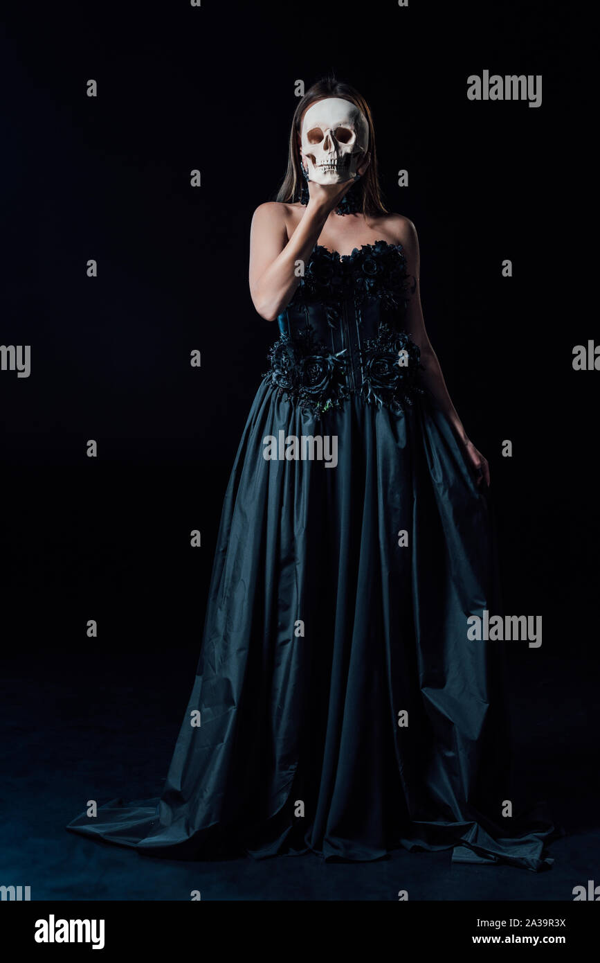 scary vampire girl in black gothic dress holding human skull in front of  face Stock Photo - Alamy