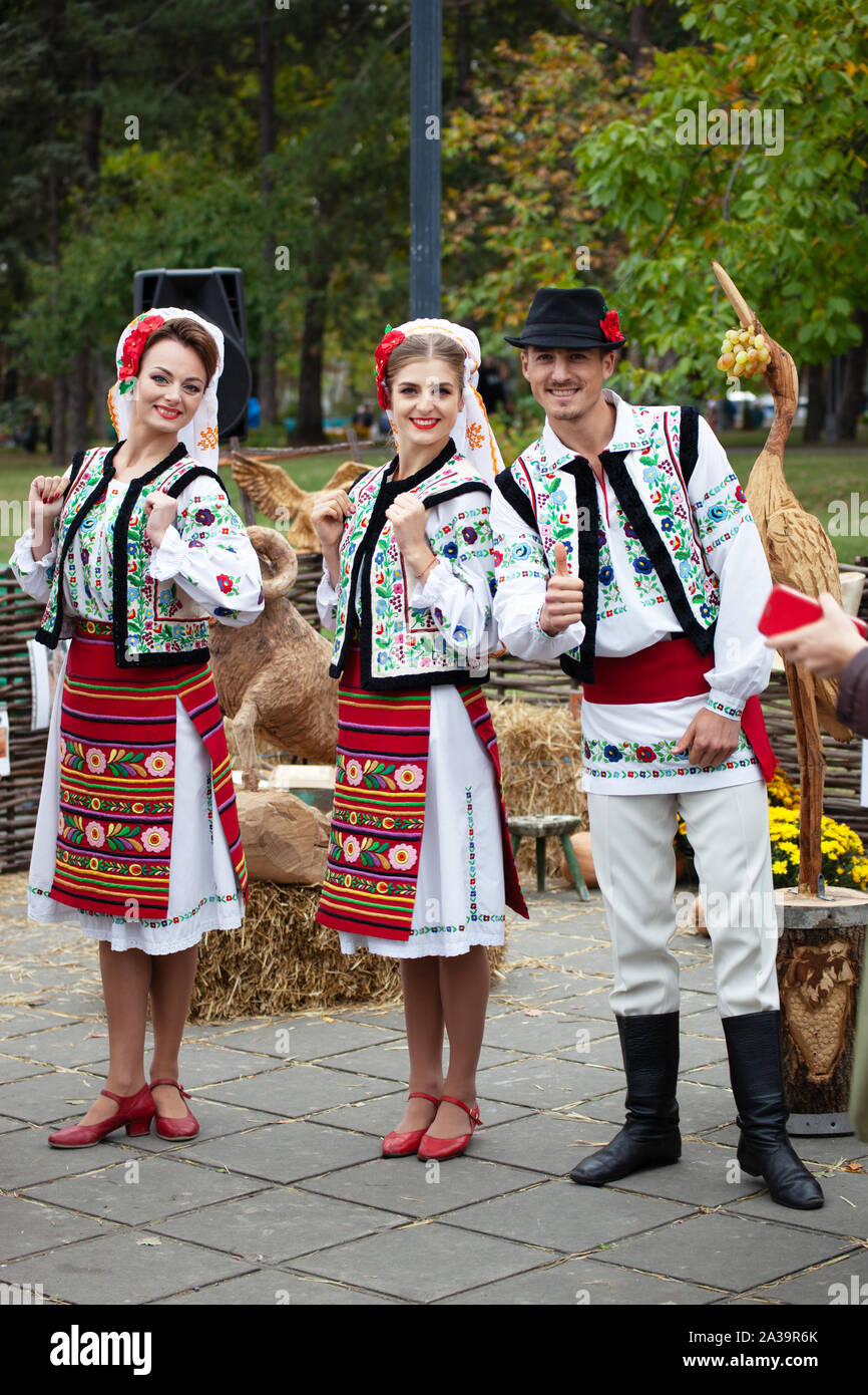 Chisinau, Moldova - October 5, 2019: Two young women and one men in traditional Balkanic costumes at a festival in Chisinau, the capital of Moldova. R Stock Photo