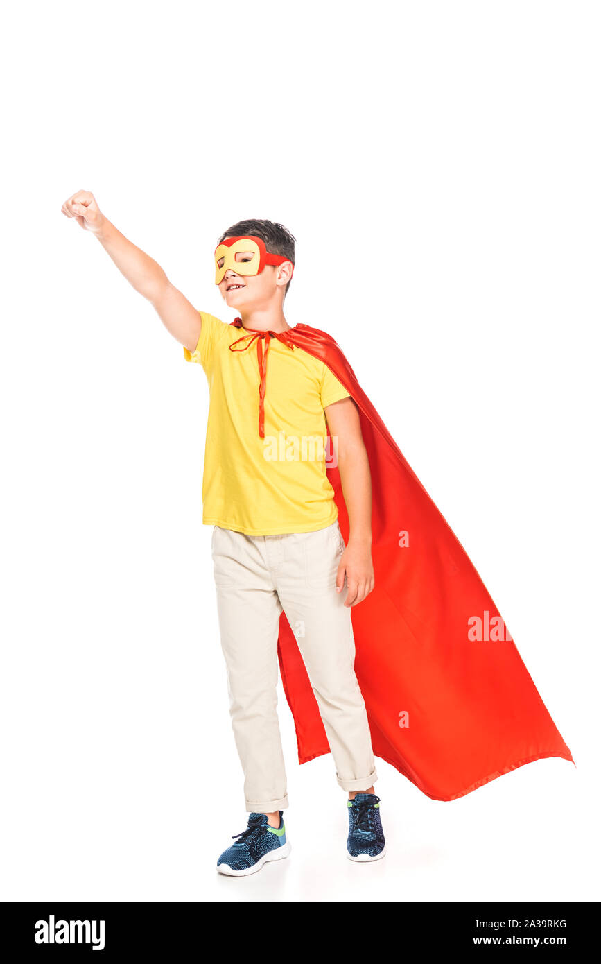 full length view of kid in mask and hero cloak holding fist up isolated on white Stock Photo