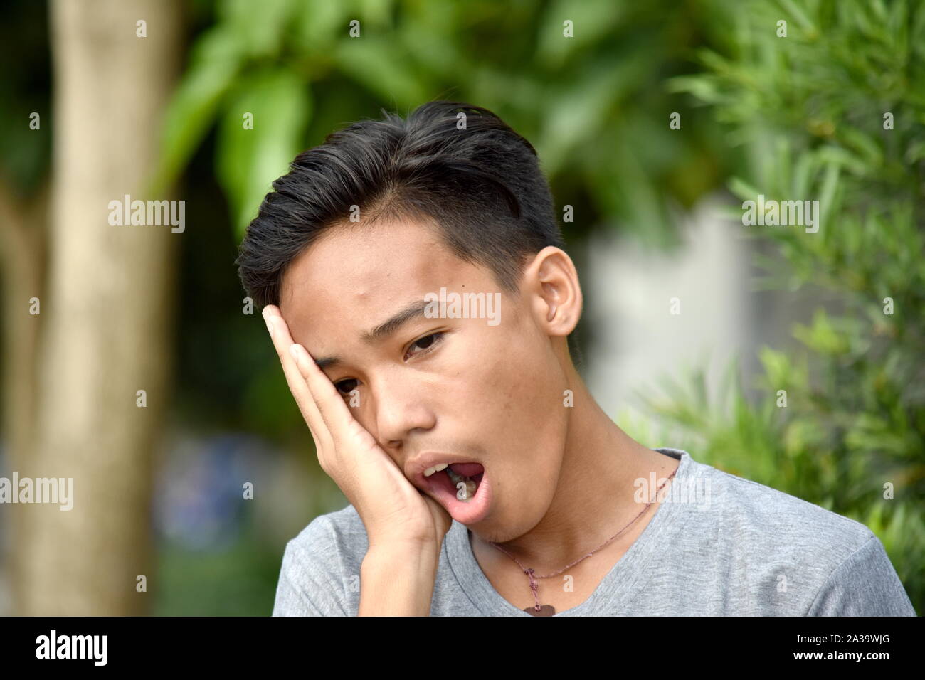 A Yawning Handsome Diverse Boy Stock Photo