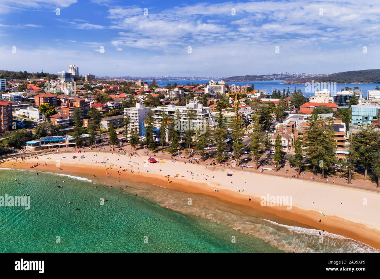 Smooth water surface of Pacific ocean rolling to clean sand of Manly beach on Northern beaches of Sydney - elevated aerial panorama with view to Sydne Stock Photo